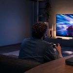 Joueur de cloud gaming dans un salon moderne, connecté en Ethernet à un routeur Wi-Fi devant un écran de jeu de course.
